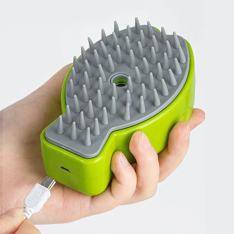 Hand holding a green cleaning brush with bristle side up, USB charging cable beside it
