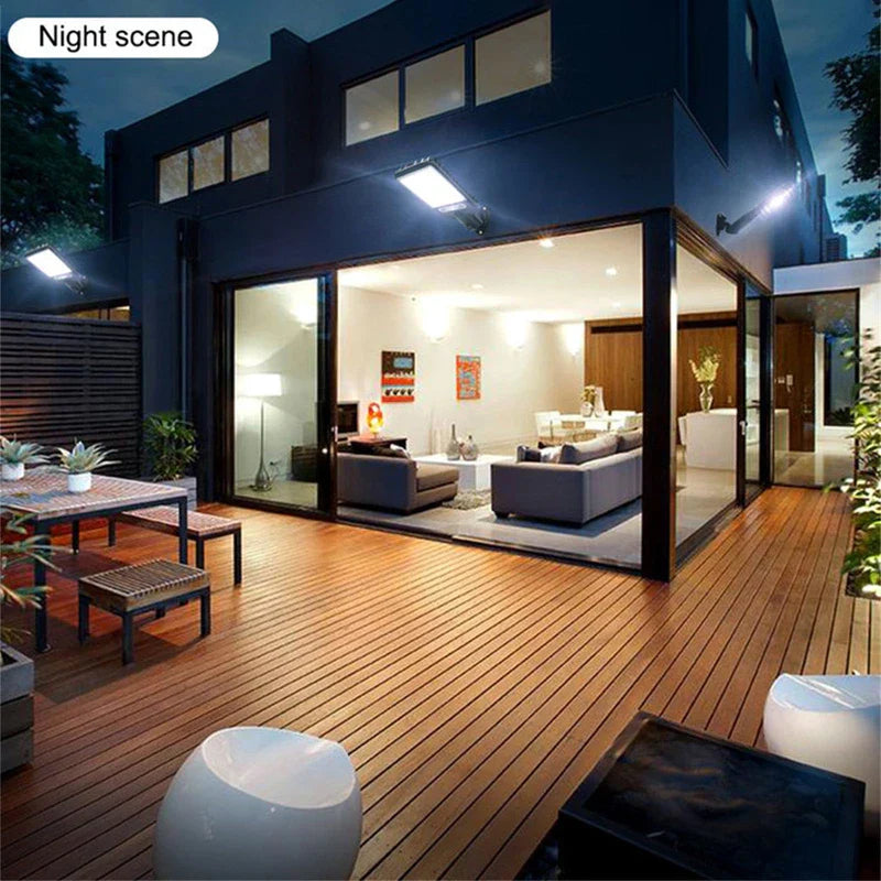 Night view of modern home deck with outdoor wall light bulb fixtures, sliding glass doors, and indoor living space visible