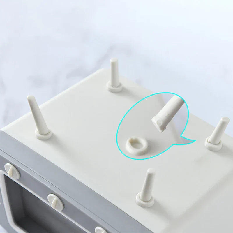 Underside view of a retro TV-shaped tissue box holder showing removable legs, with one leg detached