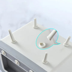 Underside view of a retro TV-shaped tissue box holder showing removable legs, with one leg detached