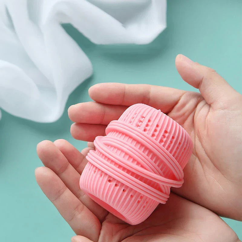 Hands holding a pink ribbed cleaning ball against teal background with white fabric