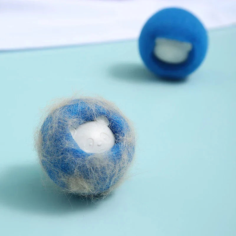 Dos artículos esféricos azules, el frontal cubierto de pelo de mascota claro con un detalle de panda blanco, sobre una superficie azul claro.