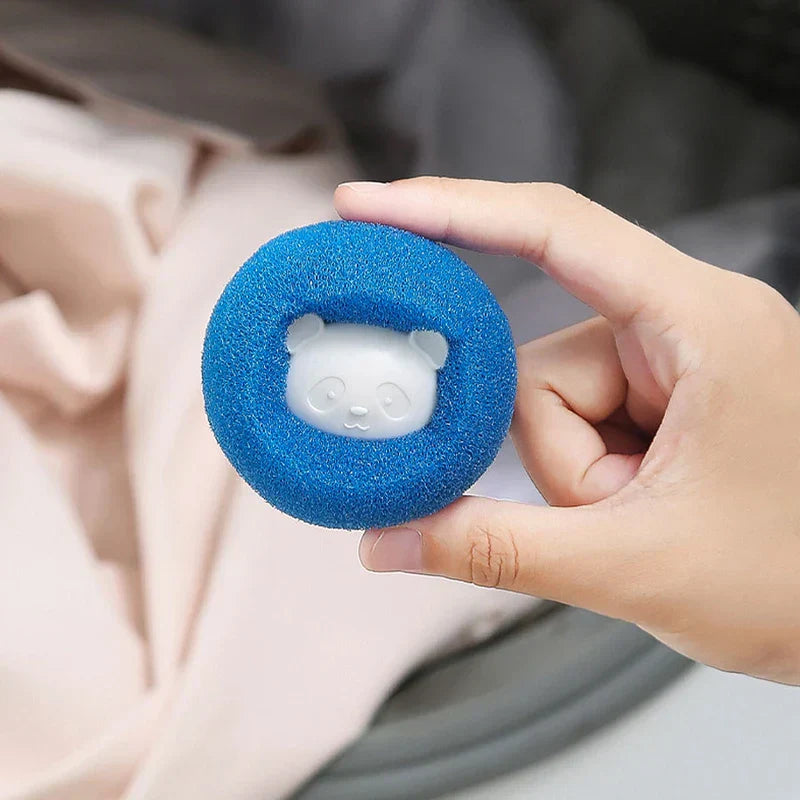 Una mano sostiene una bola de lavandería azul en forma de anillo con un detalle de cara de panda blanco en su centro.
