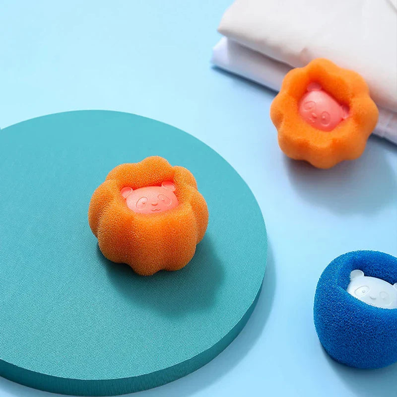 Una bola de lavandería naranja con forma de flor sobre un círculo verde azulado; bolas de lavandería naranjas y azules a juego están al fondo.