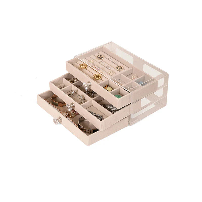 Three drawers of a beige ring necklace earring display storage box are partially pulled out, with various jewelry inside.