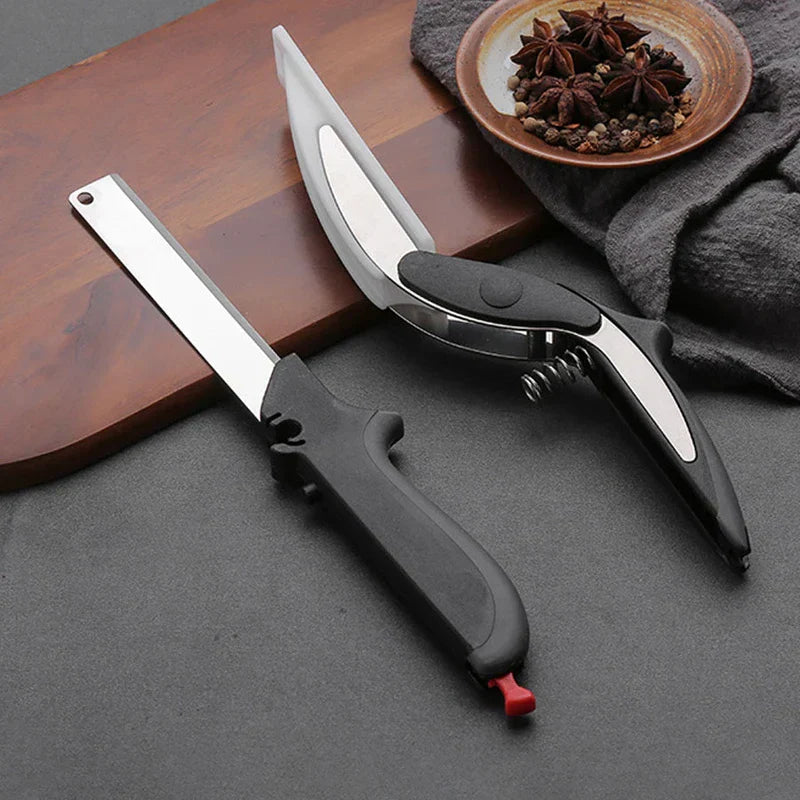 Ergonomic black and silver rotary cutter tool shown with kitchen cutting board, spices, and cloth on grey surface
