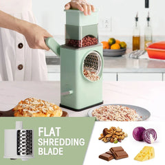 Hands operate a light green drum grater with flat shredding blade, processing peanuts; pizza and grated nuts sit nearby.