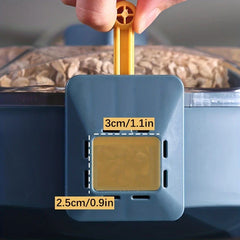 Fingers pulling a yellow tab on a blue rice dispenser lid, with grain visible behind, labeled with 3cm/1.1in and 2.5cm/0.9in dimensions
