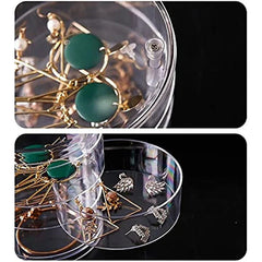 Clear jewelry organizer box with stacked trays, one open showing earrings and rings inside.