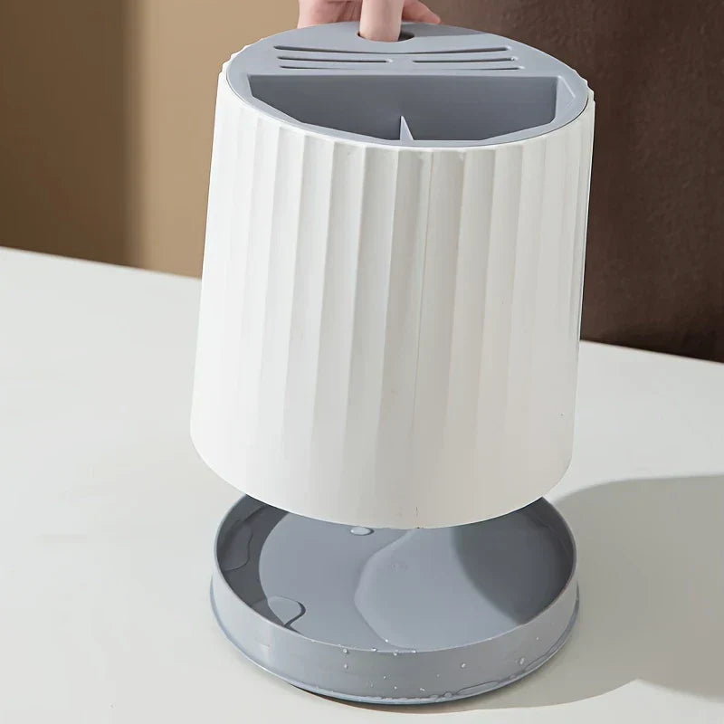 Hand lifting a white rotating kitchen utensil holder to reveal water in its gray bottom drip tray.