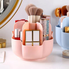 Pink petal-shaped makeup brush holder holding lipsticks, makeup brushes, and other cosmetics on a white vanity surface.