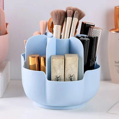 Light blue petal-shaped makeup brush holder holding makeup brushes, lipsticks, and other beauty items on a white countertop.