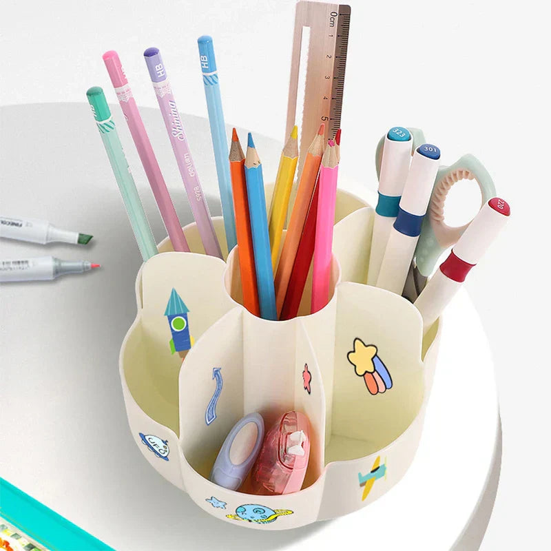 Cream 360° rotating makeup brush holder with space-themed stickers, filled with pens, pencils, scissors, and stationery, placed on a white desk