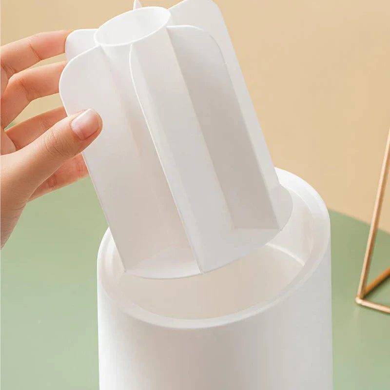 Hand lifts the divided inner insert out of a matte white rotating makeup brush holder.
