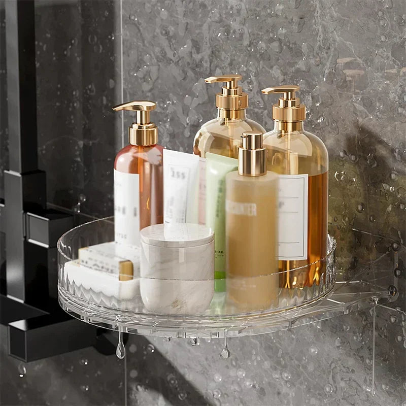 Clear rotating corner shelf holding various bathroom toiletries, with a spice rack cabinet mounted on a wet tiled wall.