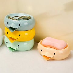 Stacked blue, yellow, green duck soap dish holders, plus a peach duck soap dish holder with pink soap beside them