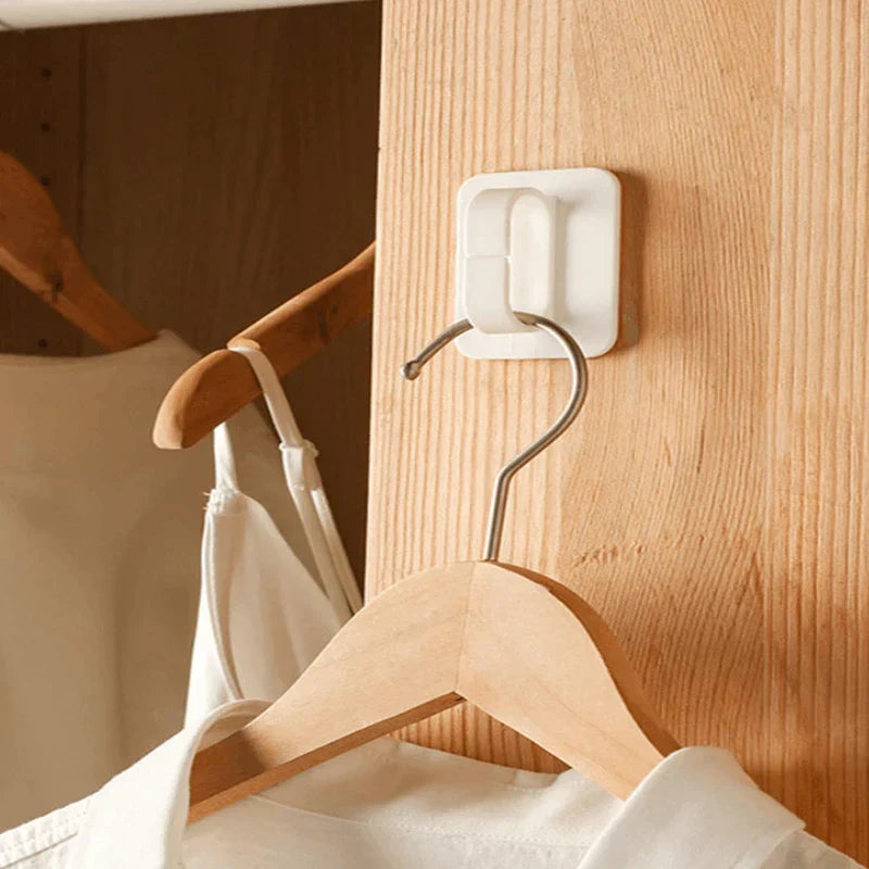White wall hook hanger mounted on a wooden closet surface holding a wooden clothes hanger with a white shirt