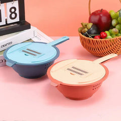 Two vegetable slicer grater sets (blue and orange) on a pink surface with a fruit basket and calendar in the background