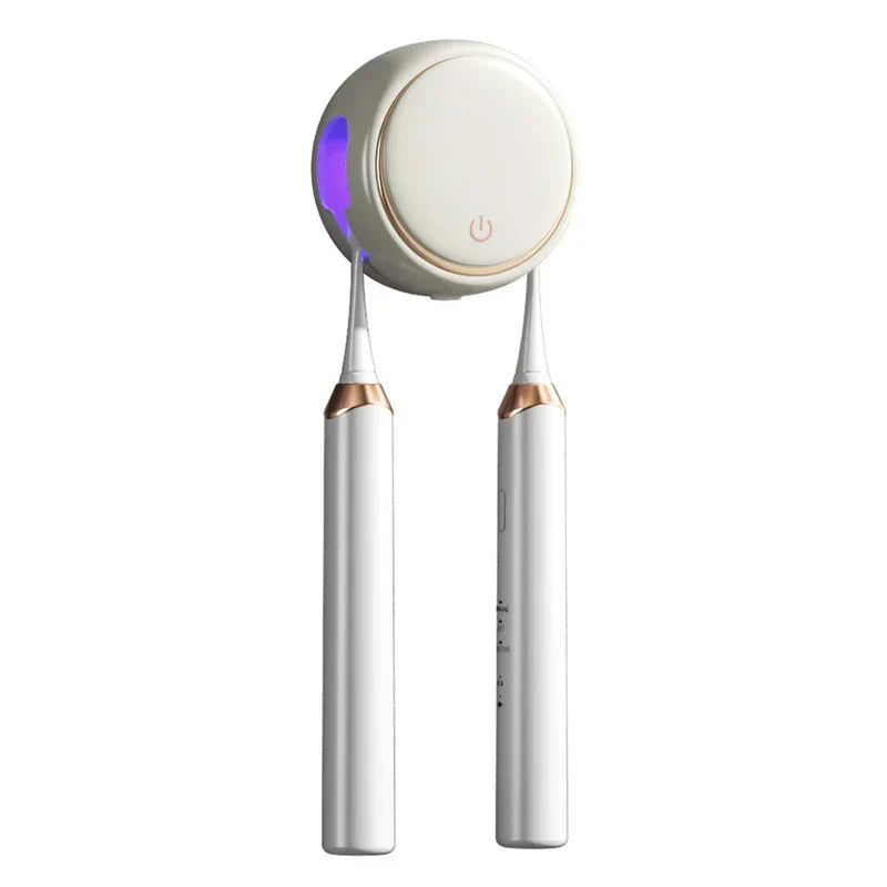 White wall-mounted toothbrush sanitizer holder with a gold trim, holding two electric toothbrushes and emitting a purple light inside.