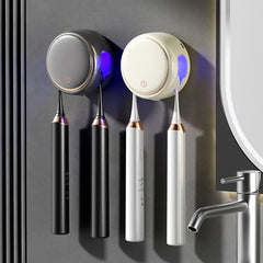 Toothbrush Sanitizer Holder - Two wall-mounted toothbrush sanitizer holders (black and white) each holding two electric toothbrushes, near a chrome faucet on gray wall