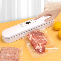 A hand presses a button on a white bag heat sealer sealing meat and sausages on a yellow table