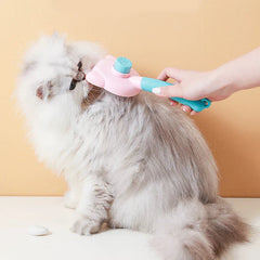 A person uses a pink and teal pet self cleaning slicker brush to groom a fluffy light gray cat