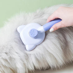 A hand uses a light purple pet self cleaning slicker brush to groom thick light gray pet fur