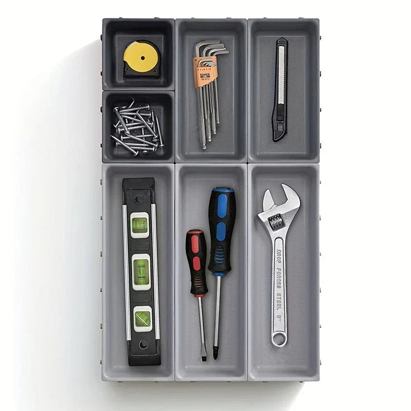 Interlocking gray storage bins arranged in a grid holding assorted small hand tools and hardware