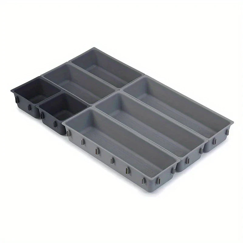 Modular interlocking storage bins in varying sizes, arranged in a connected layout in dark and light gray shades.