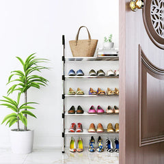 Estante para zapatos de seis niveles que sostiene pares de zapatos, una bolsa de tela, libros y una pequeña planta en maceta, ubicado cerca de una puerta junto a una planta grande de piso