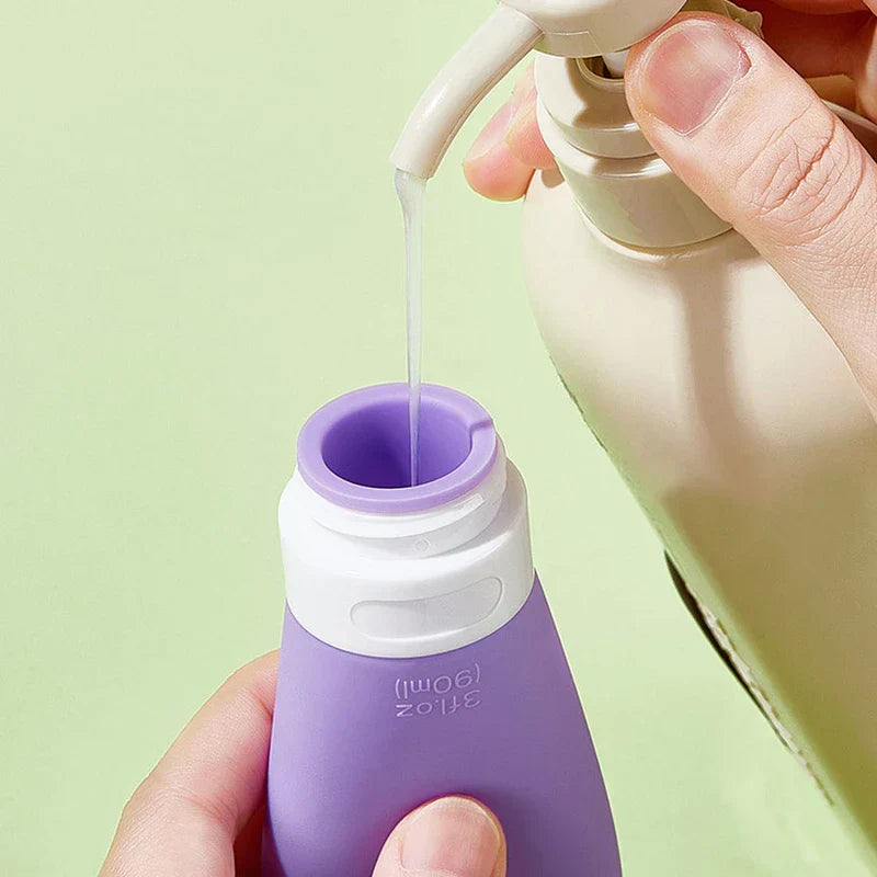 Hands pouring liquid from a pump bottle into a purple silicone travel toiletry container