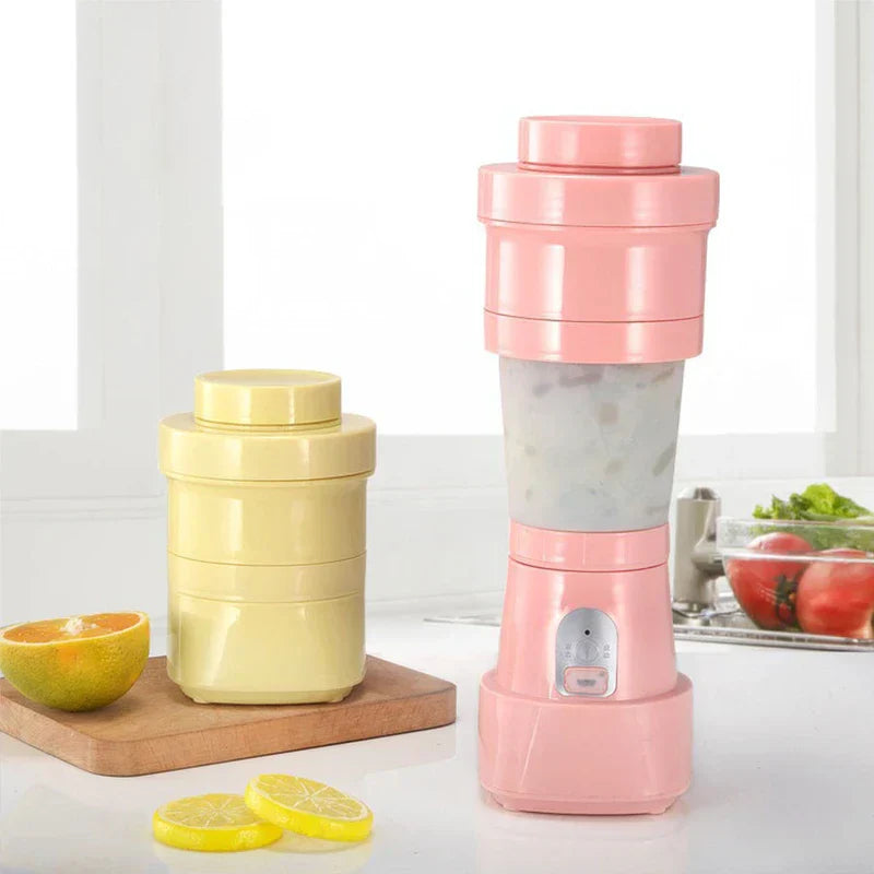 Rosa Smoothie-Maker für eine Portion mit gelbem Aufbewahrungsbehälter, Zitrusfrüchten und Küchenzutaten im Hintergrund auf einer Arbeitsplatte
