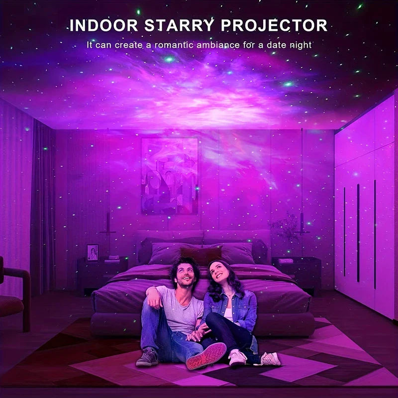 Room with purple ceiling projection from an indoor galaxy projector, two people sitting on a bedroom floor looking up