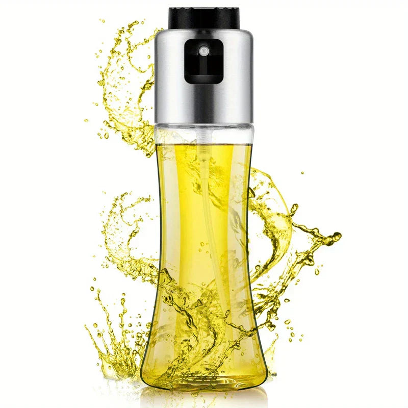 Glass oil sprayer bottle with yellow liquid inside, surrounded by splashes of oil against a white background