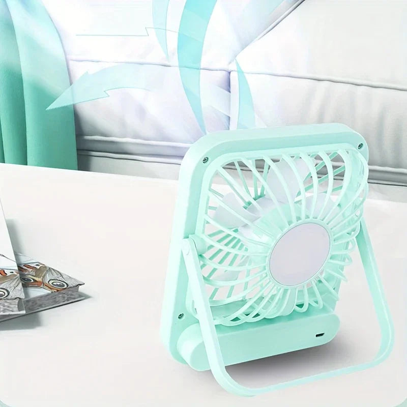 Light mint desktop quiet fan on a white table, with a pillow and curtain in the background