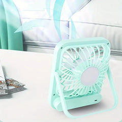 Light mint desktop quiet fan on a white table, with a pillow and curtain in the background