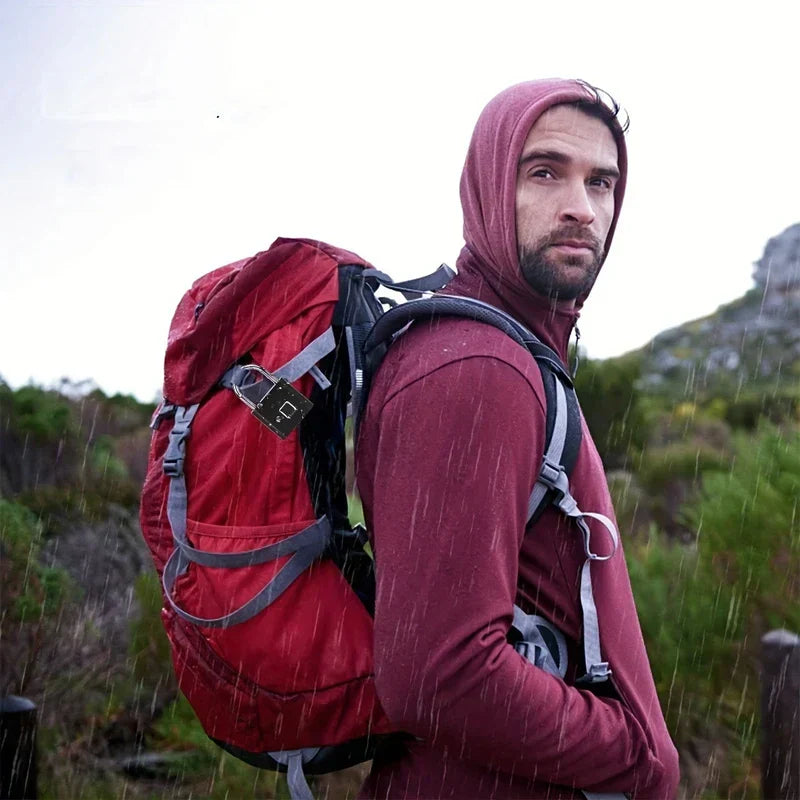 Un excursionista bajo la lluvia lleva una mochila roja asegurada con un candado biométrico