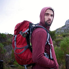 Un excursionista bajo la lluvia lleva una mochila roja asegurada con un candado biométrico