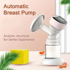 Automatic electric breast pump with clear milk bottle, displayed on light surface with decorative leaves, yellow block, and fruit slices.