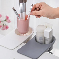A hand picks a makeup brush from a pink tulip-shaped holder, with skincare bottles in a gray caddy, paired with shoe box storage for bathroom organization.