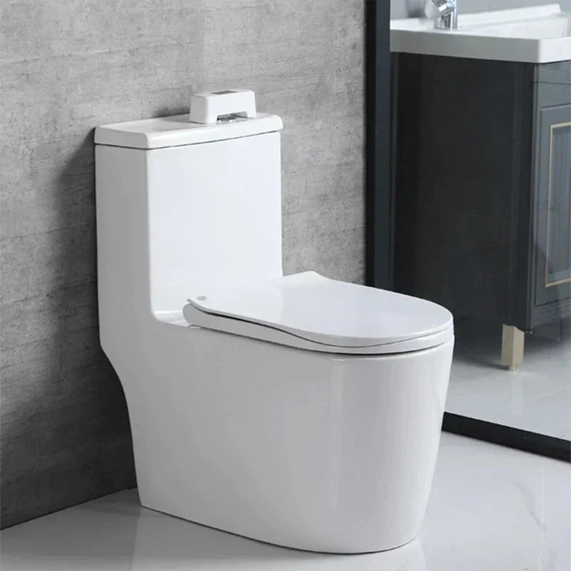 White one-piece toilet with smart toilet sensor mounted on tank top, in a bathroom with grey wall and vanity