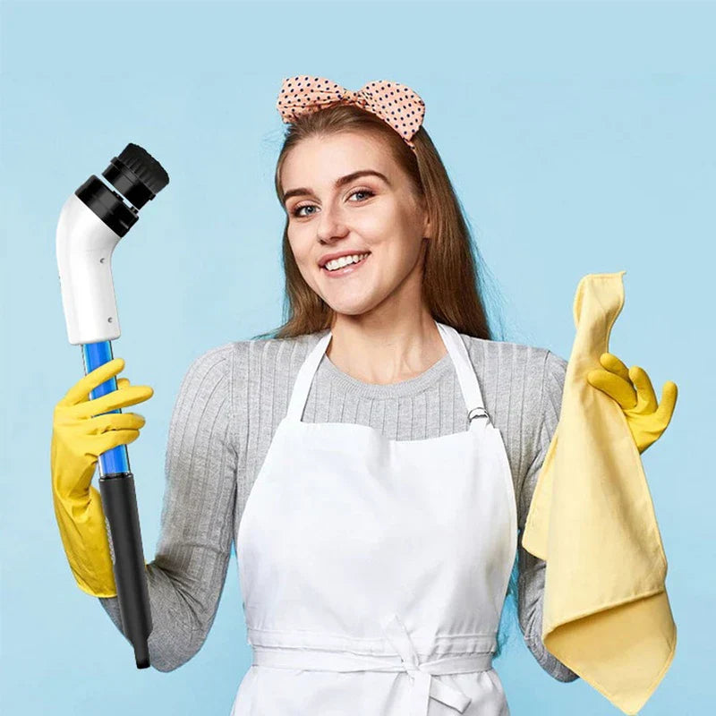 Smiling woman in a white apron and yellow rubber gloves holds a cleaning scrub brush and a yellow cloth.