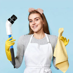 Smiling woman in a white apron and yellow rubber gloves holds a cleaning scrub brush and a yellow cloth.