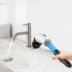 Hand holding a cleaning scrub brush while cleaning a bathroom sink with a running faucet
