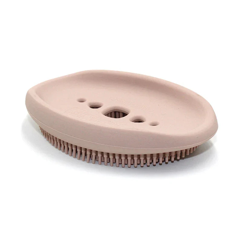 Dish Scrubber Brush - Light pink oval soap holder with drainage holes and raised silicone bristles on the bottom edge