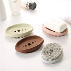 Dish Scrubber Brush - Assorted neutral-toned oval soap holders, one holding a bar of white soap, arranged on a white countertop