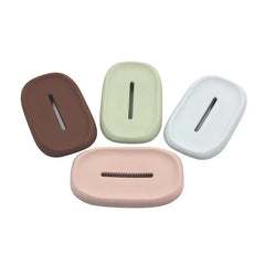 Dish Scrubber Brush - Four oval silicone brushes in brown, light green, white, and pink, each with a central slot.