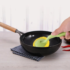 Soap dispensing brush scrubbing a pot with soap suds