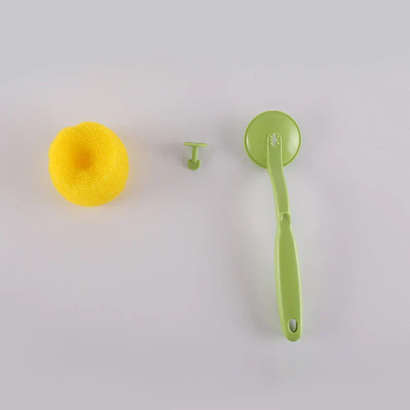 Soap Dispensing Brush - Disassembled brush parts: yellow sponge head, small green fastener, green brush handle with head base, laid on a plain light gray surface.