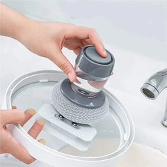 Dish Brush Soap Dispensing - Hand pressing the top button of the scrubber while holding it over a soapy water basin